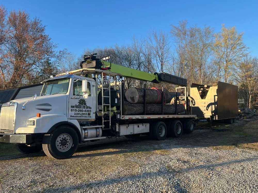 New Horizon crane truck with a trailer loaded with large logs